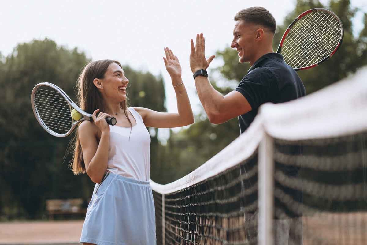 A female and a male tennis player giving each other a high five at the net